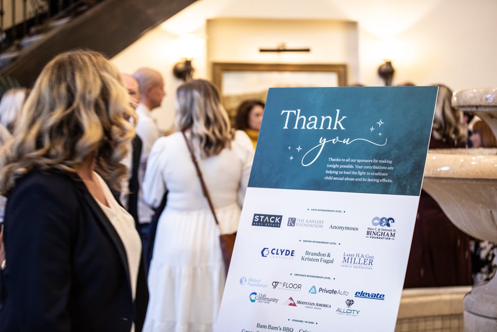 Sponsor 'Thank You' signage at the Saprea gala, with guests in the background
