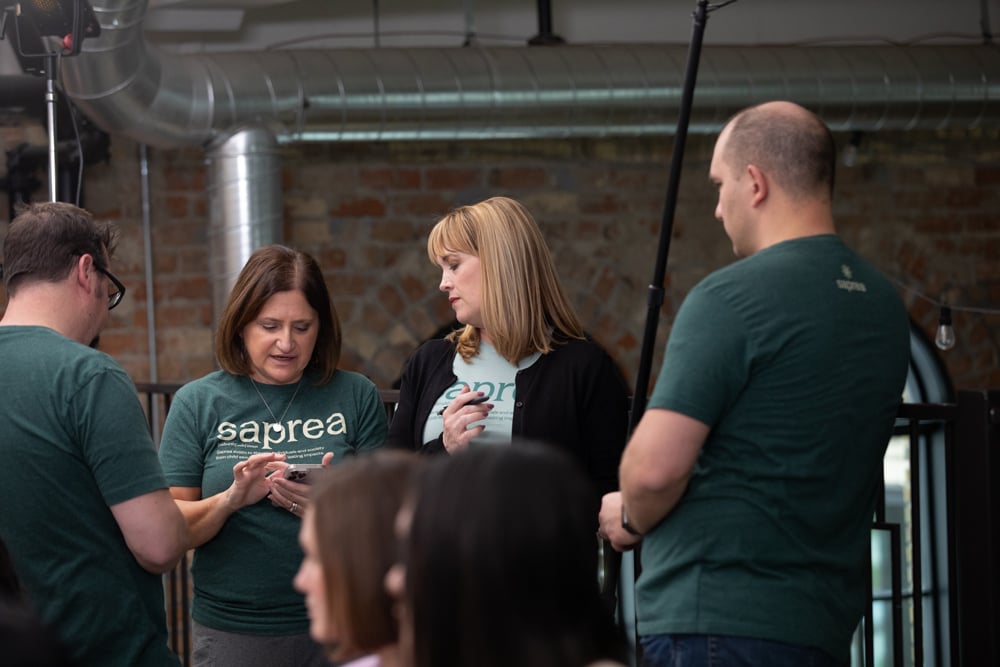 Crew in Saprea t-shirts reviewing footage on set between takes