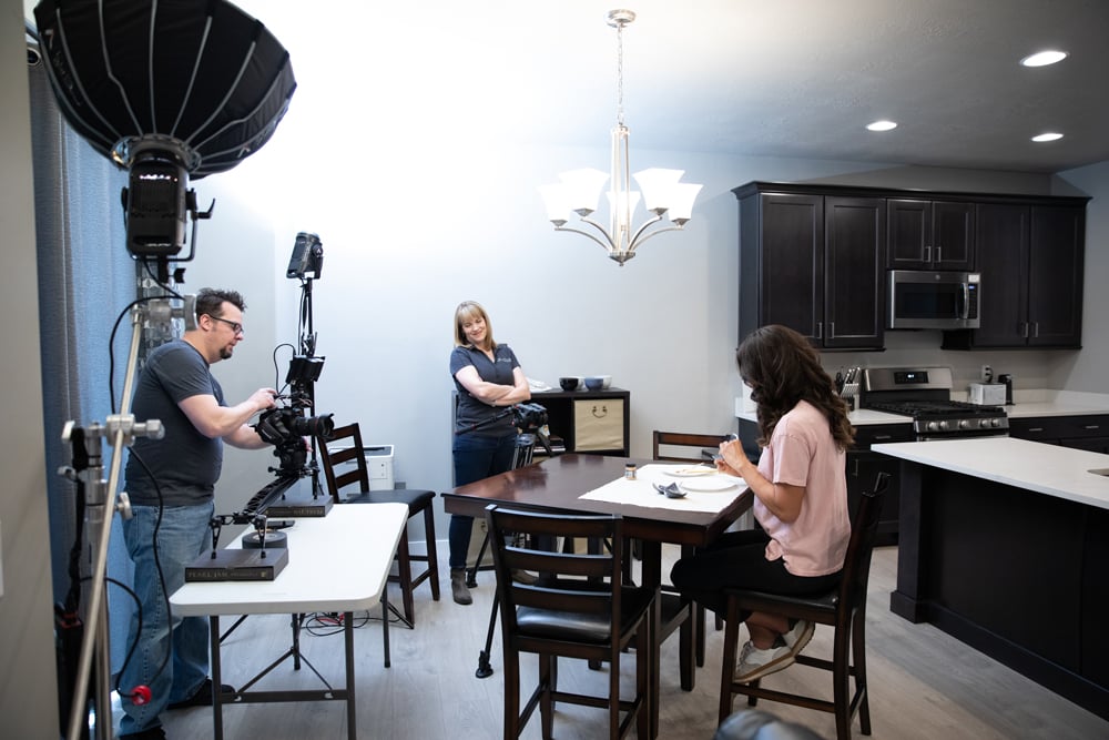 Camera and lighting setup for a home dining room scene, part of a video shoot